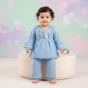 Baby girl nature-themed outfit featuring an embroidered tunic with butterflies and mushrooms, ruffled sleeves, and matching trousers on a dusty rose background.